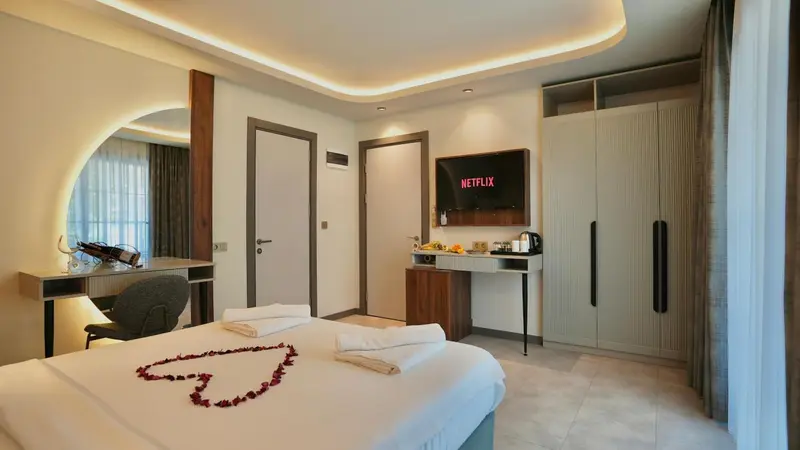 Une chambre d'hôtel moderne avec un lit décoré de pétales de fleurs et un téléviseur mural.