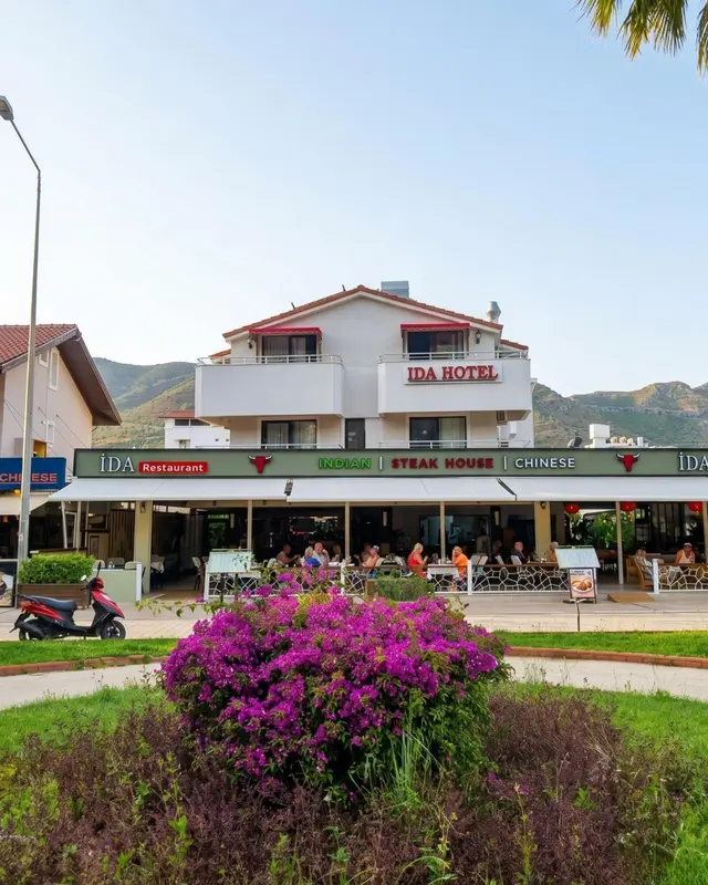 Façade d'un bâtiment blanc avec des balcons et des restaurants en rez-de-chaussée.