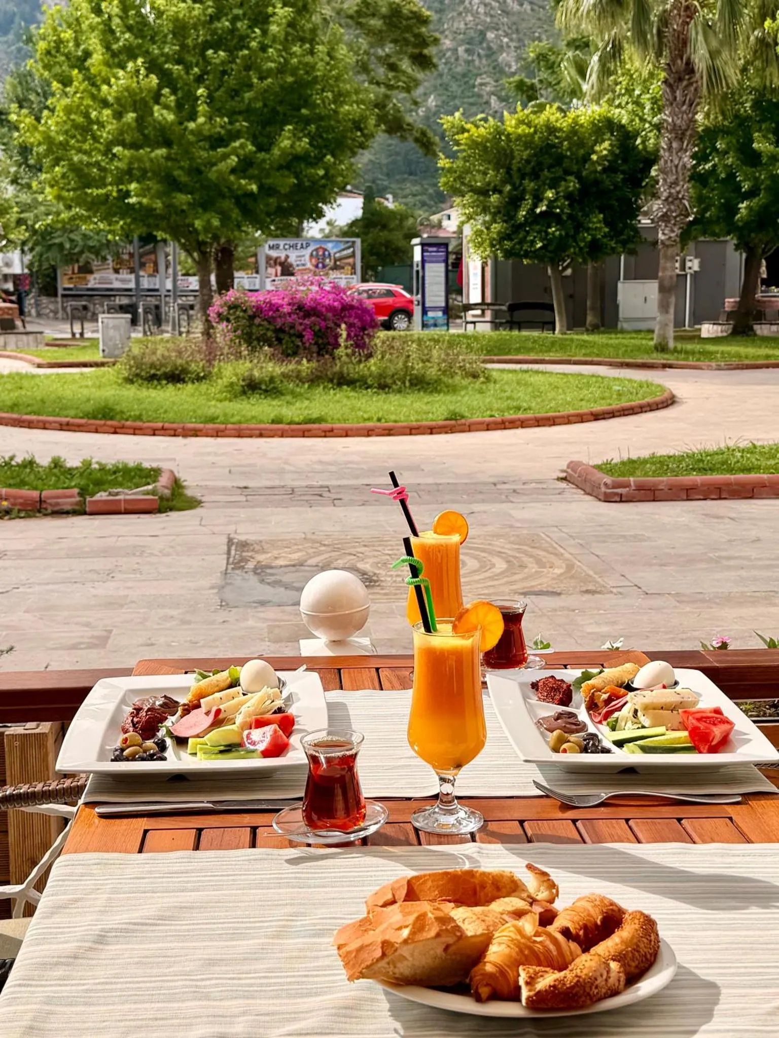 Une table est dressée avec un petit-déjeuner copieux, des viennoiseries et des boissons fraîches.