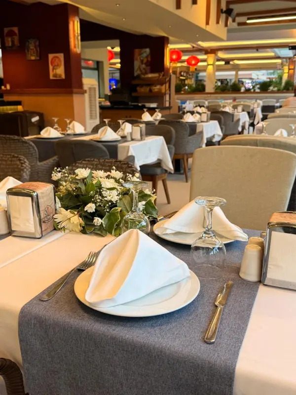 Une table dressée avec des couverts et une décoration florale dans une salle lumineuse.