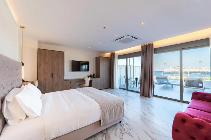 Chambre lumineuse avec un grand lit et un accès à une terrasse.