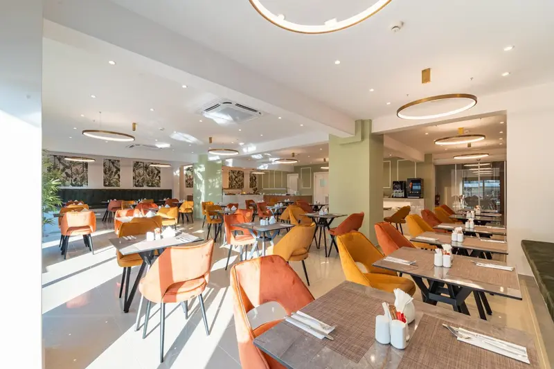 Une salle lumineuse avec des tables dressées pour le repas.