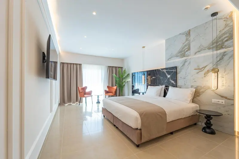Une chambre lumineuse avec un grand lit et un téléviseur mural.
