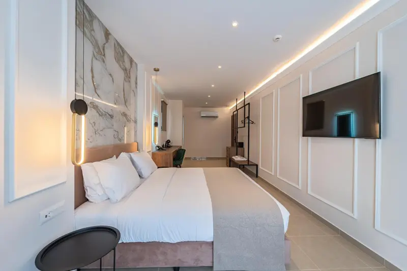 Une chambre lumineuse avec un grand lit et une télévision murale.