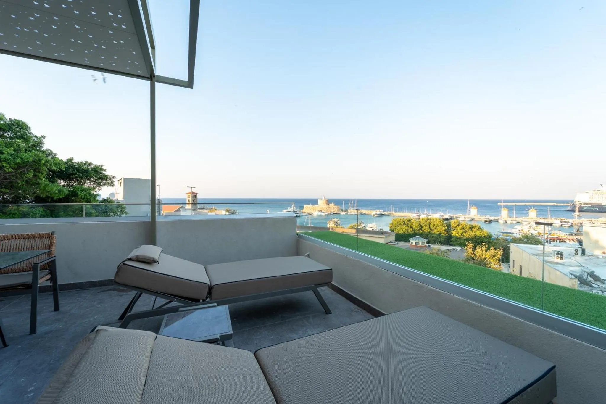 Terrasse aménagée avec transats et vue sur la mer et la ville.