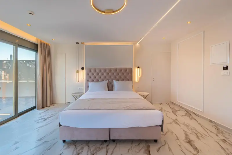 Une chambre lumineuse avec un grand lit et un accès à une terrasse.
