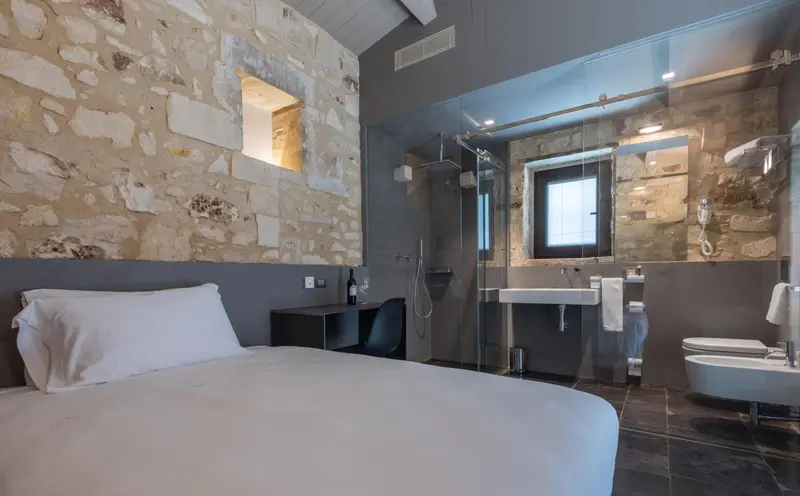 Une chambre moderne avec un mur en pierre et une salle de bain vitrée.