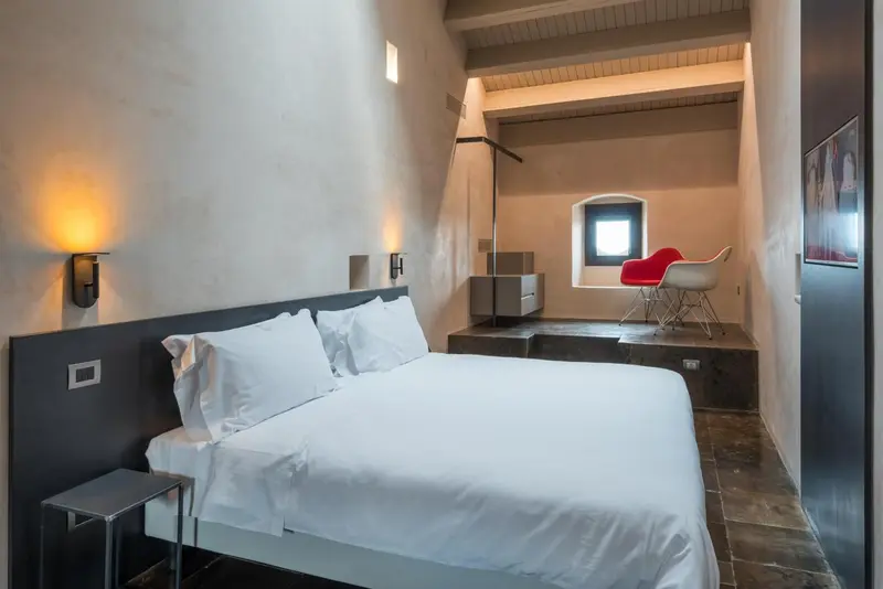 Une chambre lumineuse avec un grand lit et un coin lecture près d'une fenêtre.