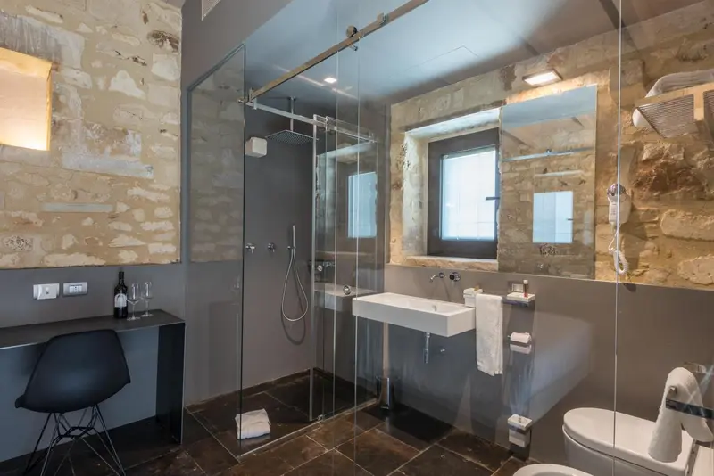 Une salle de bain moderne avec douche à l'italienne et murs en pierre.