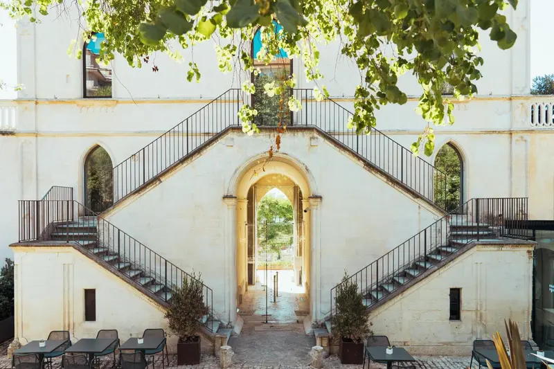 Escalier monumental en pierre menant à une arche dans un bâtiment blanc.