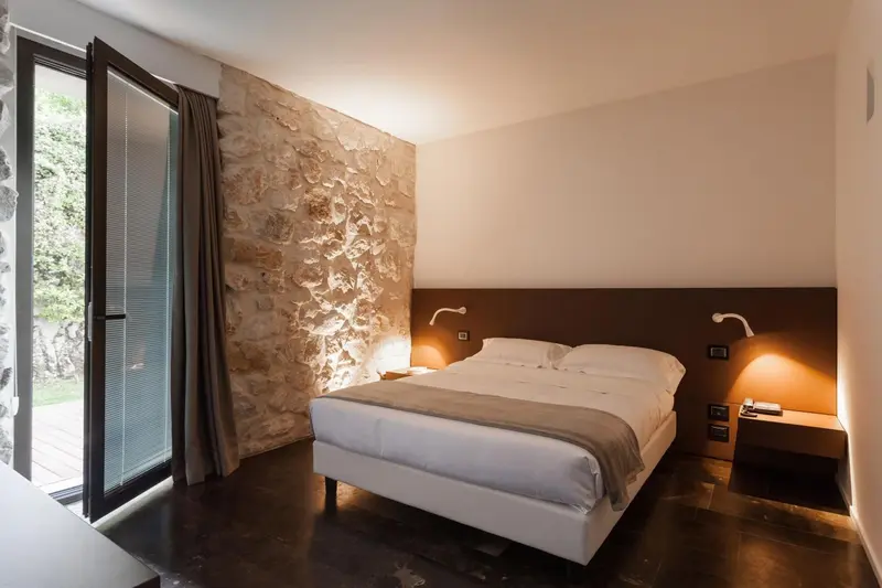 Une chambre lumineuse avec un lit double et un mur en pierre.