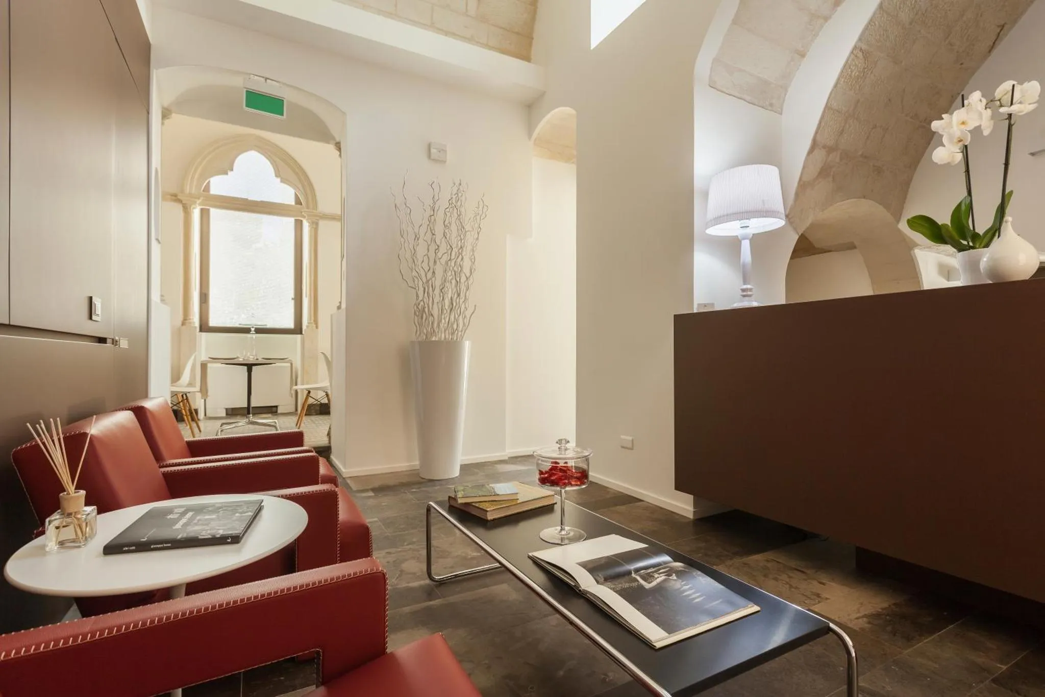 Espace de détente avec canapés rouges et table basse en verre.