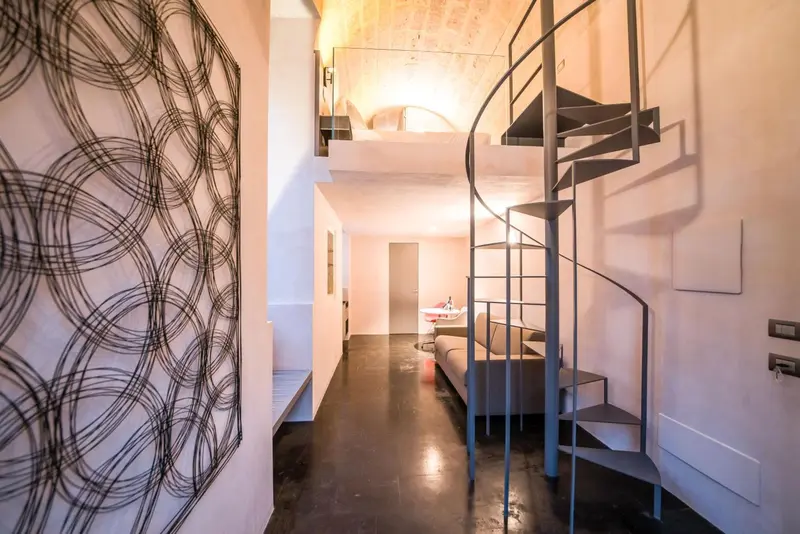 Une chambre mansardée avec un escalier en colimaçon métallique.