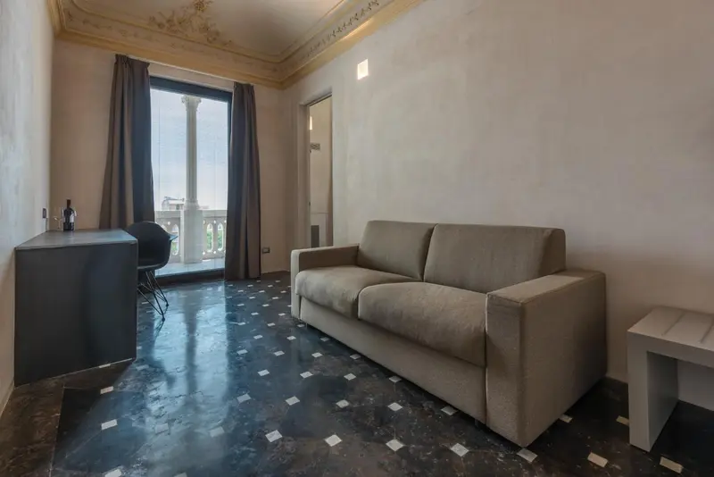Un salon lumineux avec un canapé et un bureau donnant sur un balcon.