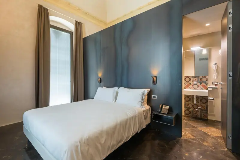 Une chambre lumineuse avec un grand lit et une salle de bain attenante.