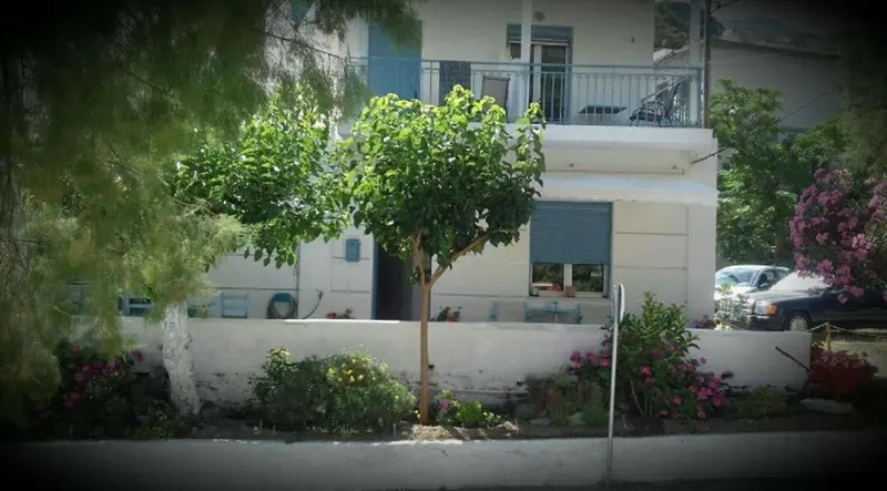 Façade d'un bâtiment blanc avec des arbustes et des fleurs devant.