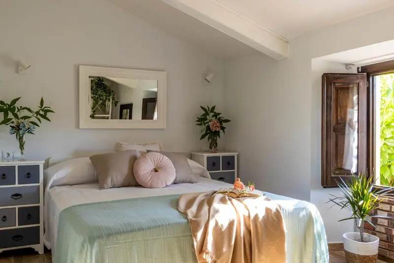 Une chambre lumineuse avec un grand lit recouvert de coussins et d'une couverture.