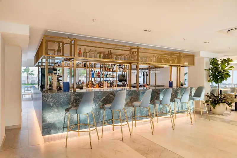 Un bar moderne avec un comptoir en marbre et des tabourets bleus.