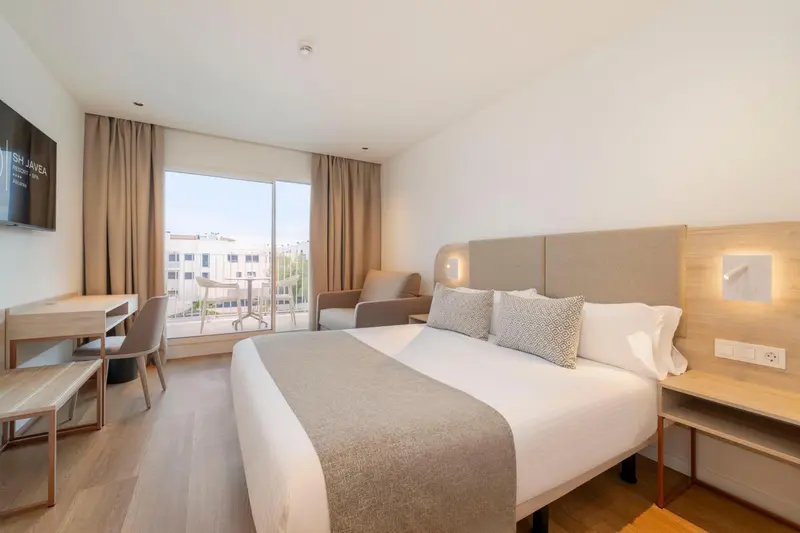 Une chambre lumineuse avec un grand lit et un accès à un balcon.