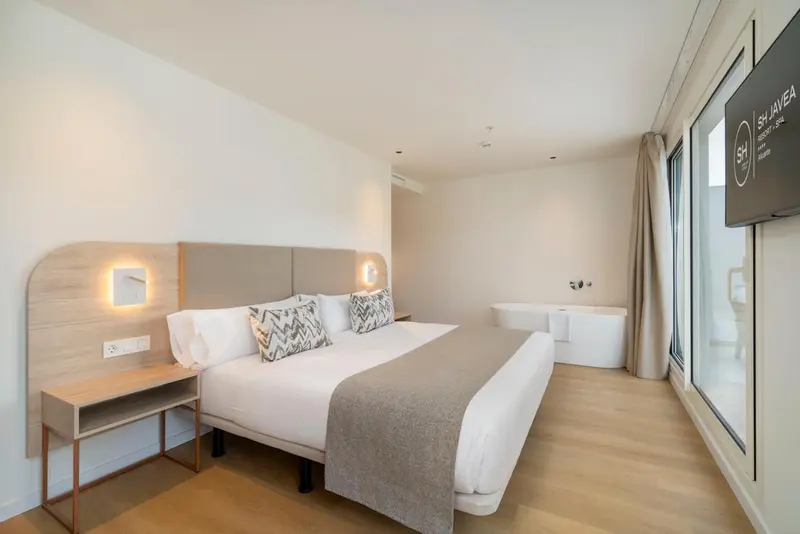 Une chambre d'hôtel moderne avec un grand lit et des luminaires muraux.
