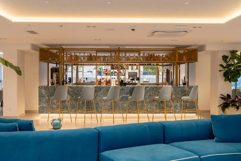 Un bar moderne avec des tabourets et un canapé bleu turquoise.