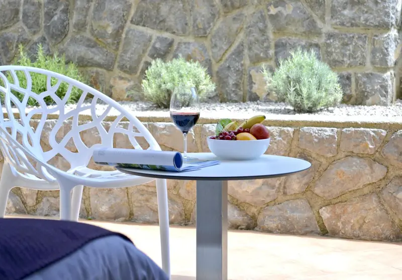 Une table basse avec un verre de vin, des fruits et un magazine sur une terrasse.