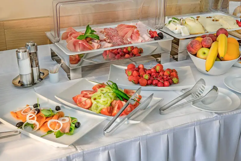 Présentation de charcuterie, de fruits frais et de crudités sur un buffet.