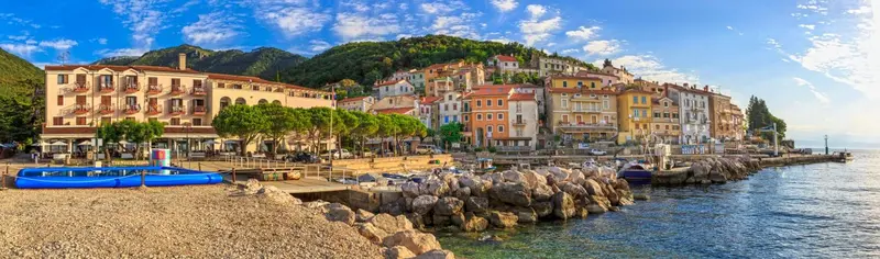 Vue panoramique d'une ville côtière avec des bâtiments colorés et une promenade en bord de mer.