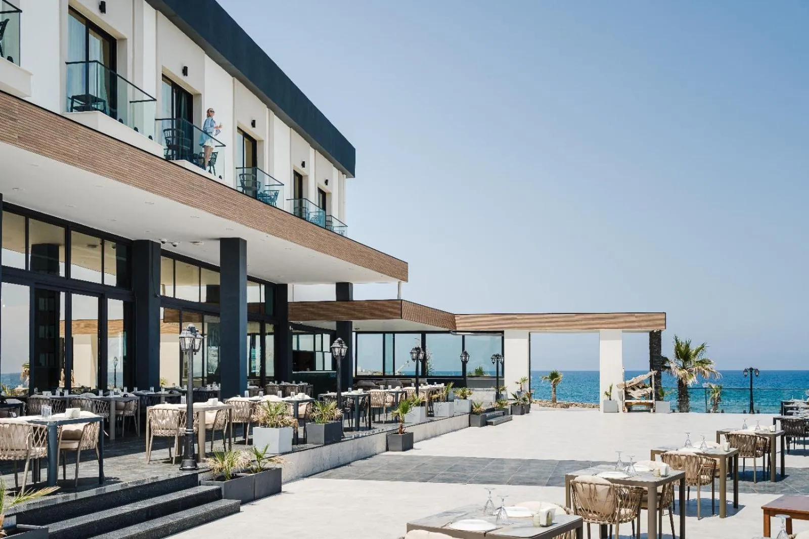 Terrasse de restaurant avec tables et chaises en extérieur, vue sur la mer.