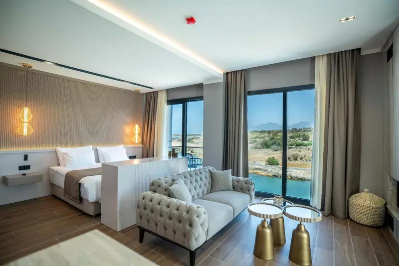 Une chambre lumineuse avec un lit et un canapé face à une grande fenêtre.