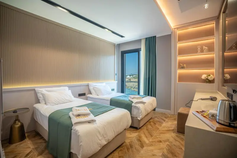 Chambre lumineuse avec deux lits simples et une vue sur la mer.