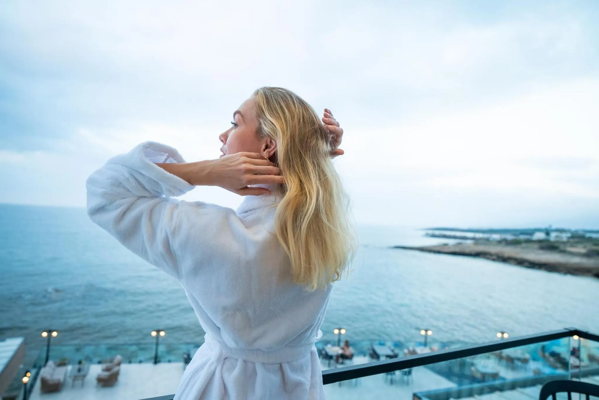 Une femme se tient sur une terrasse en admirant la vue sur la mer.