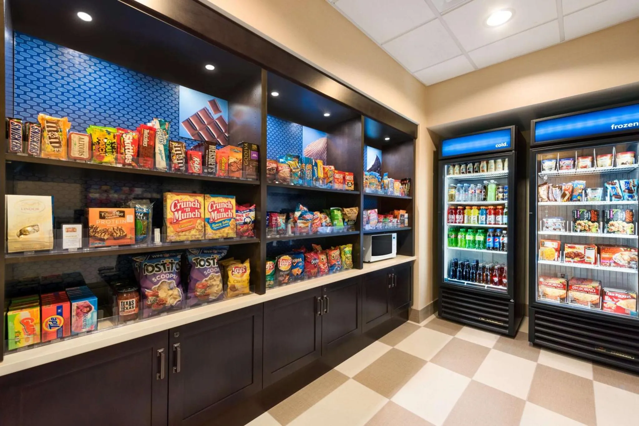 Rayonnages remplis de snacks et de boissons, avec des réfrigérateurs remplis de produits.
