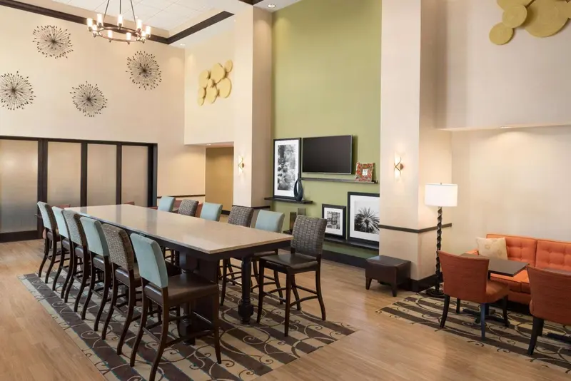 Une grande table avec des chaises est entourée de sièges confortables dans un espace lumineux et décoré.