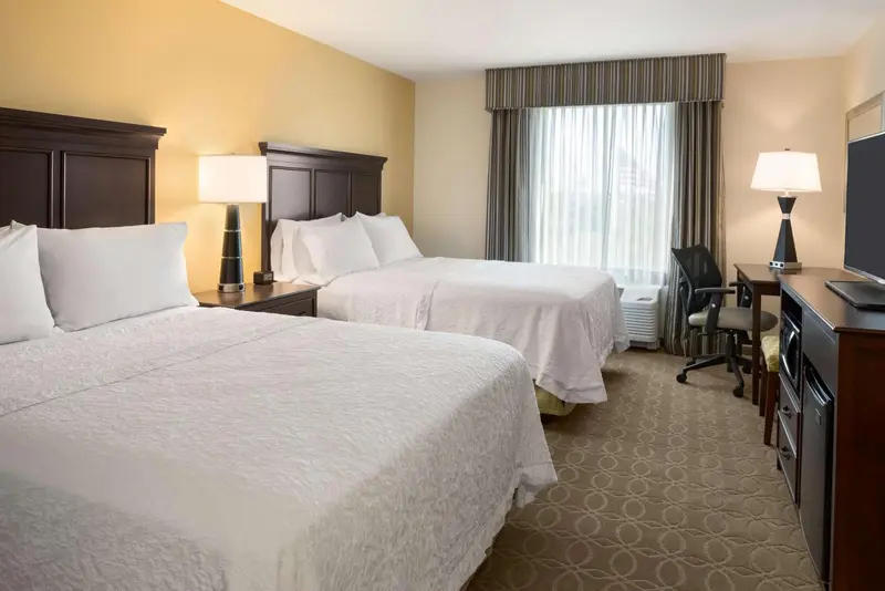 Une chambre d'hôtel avec deux lits et un espace de travail.