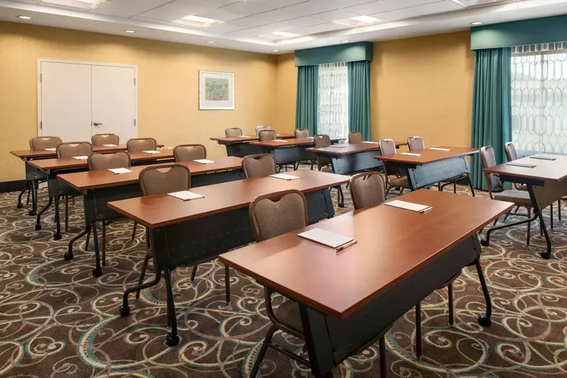 Une salle de réunion lumineuse avec des tables et des chaises disposées pour une conférence.