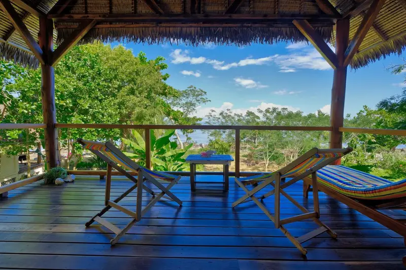 Terrasse en bois avec deux chaises longues face à la mer.