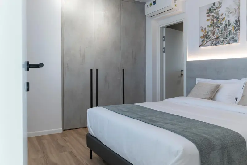Une chambre avec un grand lit et des armoires grises.