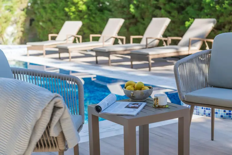 Des fauteuils et une table basse se trouvent au bord d'une piscine.