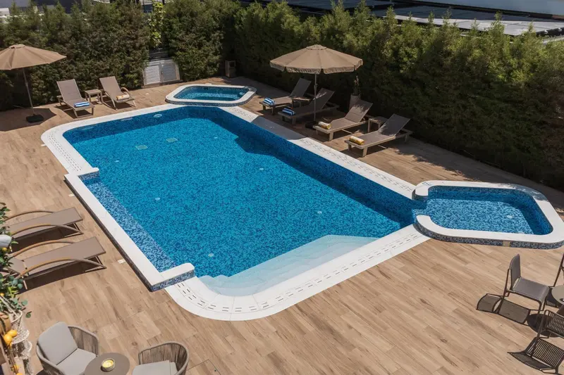 Une piscine rectangulaire entourée d'une terrasse en bois avec des transats.