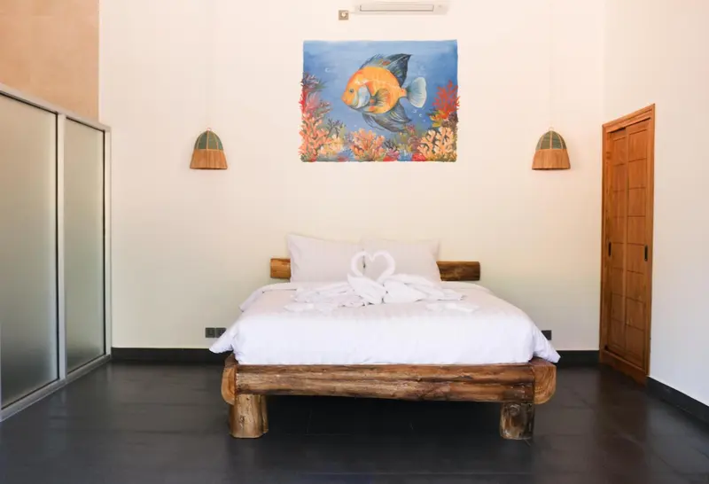 Une chambre lumineuse avec un lit décoré de serviettes en forme de cœur.