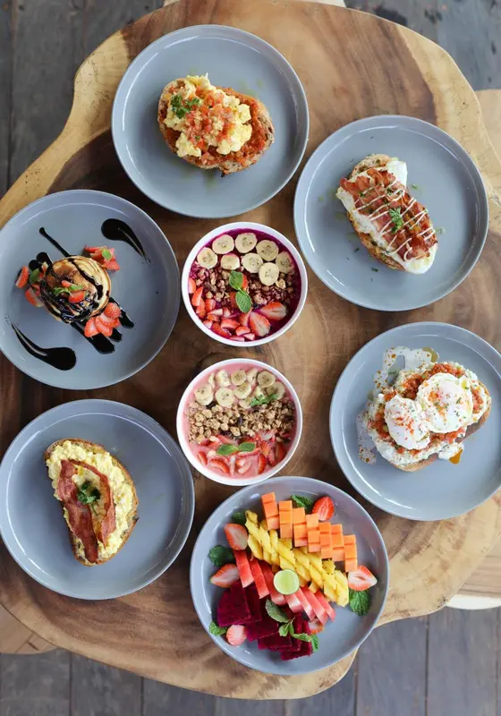 Assiettes de fruits et de plats sucrés présentés sur une table en bois.