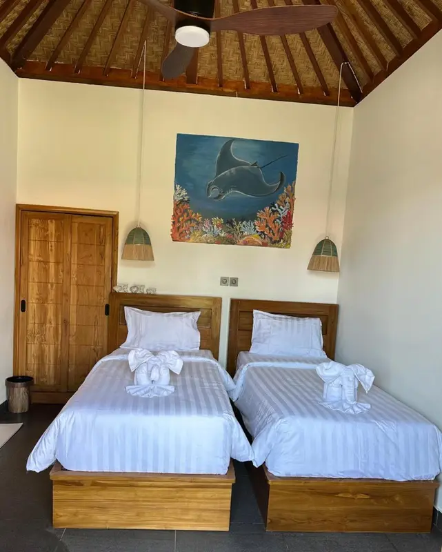 Deux lits simples dans une chambre lumineuse avec une décoration murale marine.