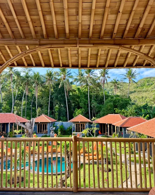 Vue sur des bungalows individuels au toit rouge, entourés d'une végétation luxuriante et d'une piscine.