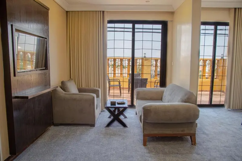 Un salon clair avec deux fauteuils et un canapé, donnant sur une terrasse.