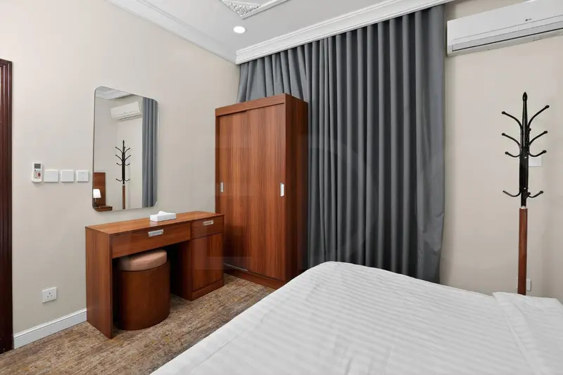 Une chambre d'hôtel avec un lit, une coiffeuse et une armoire.