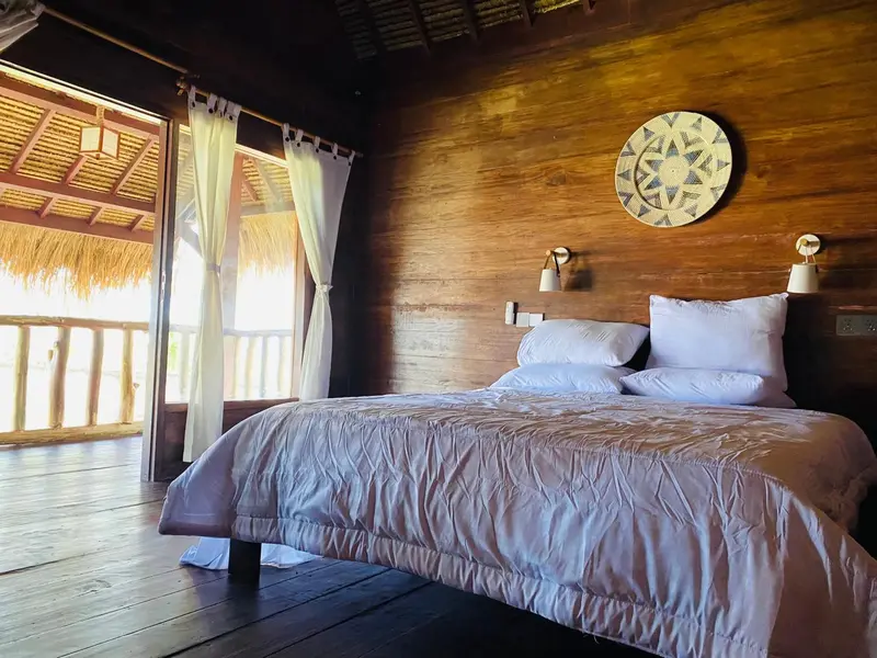 Une chambre lumineuse avec un lit recouvert d'une couette blanche et un décor mural en bois.