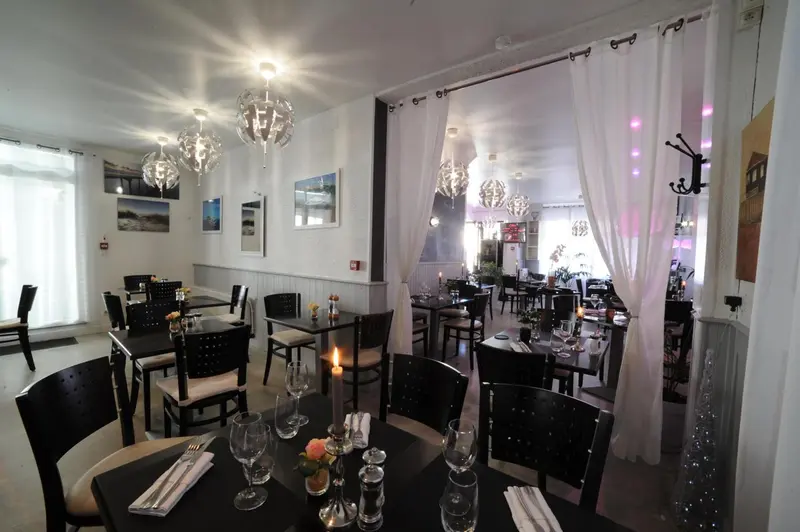 Une salle de restaurant lumineuse avec des tables dressées et une décoration soignée.