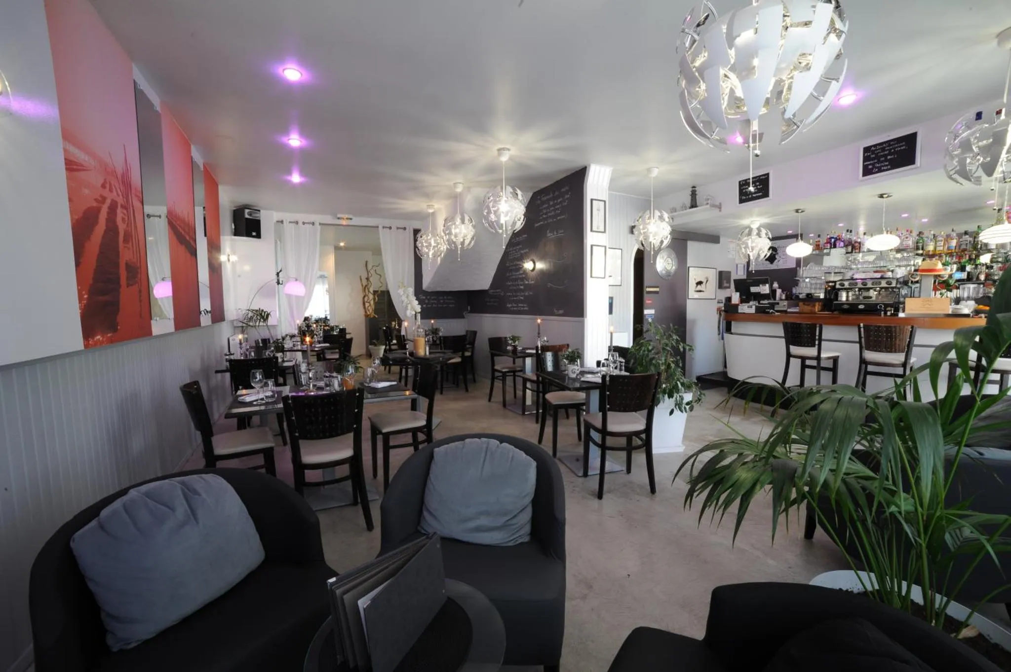 Une salle lumineuse avec des tables dressées et un comptoir de bar.