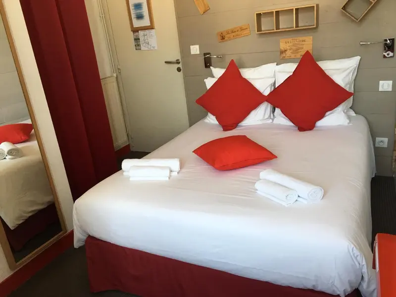 Une chambre avec un lit recouvert d'une courtepointe blanche et de coussins rouges.